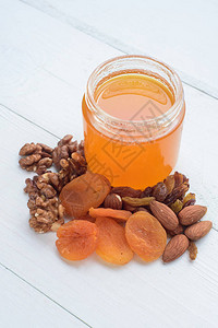 蜂蜜杏仁胡桃和干杏仁白木桌上沾图片