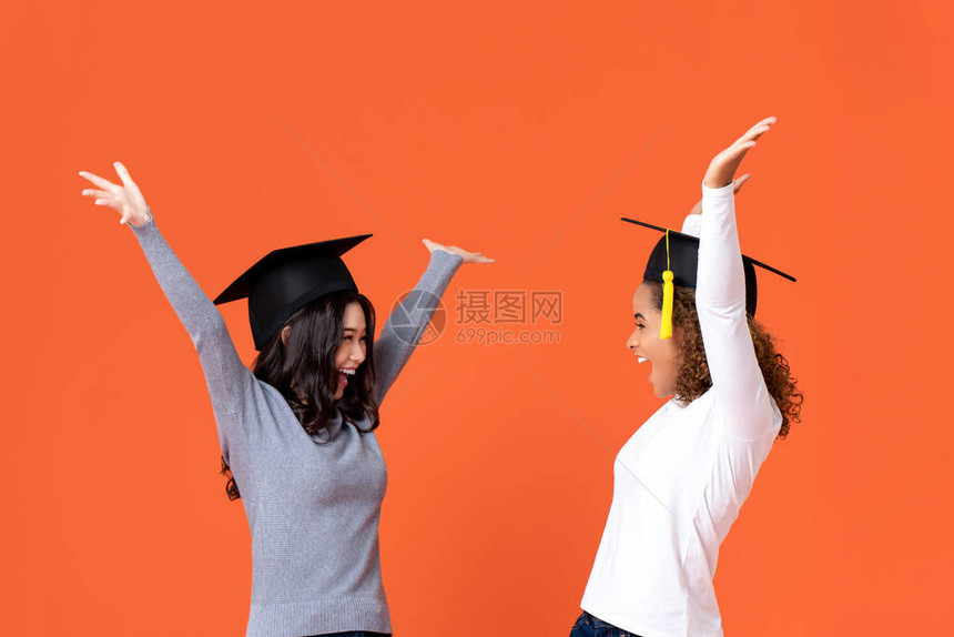 戴着研究生帽子的快乐兴奋的年轻女学生带着双手微笑图片