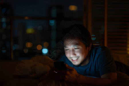 特写亚洲男人睡觉和使用智能手机进行社交网络或视频电话会议图片
