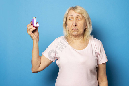 一个穿便衣T恤的老友好妇女带着孤立光背景的吸入器情感面孔麻痹过敏概念图片