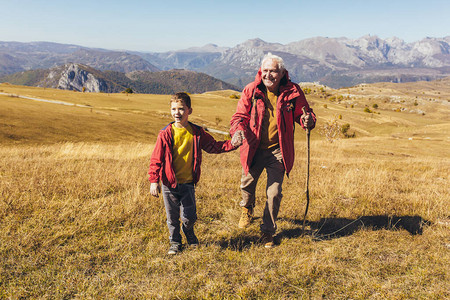 老人带着孙子在秋天的乡村散步图片