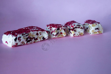 Torrone或牛轧糖棒与坚果和红色干浆果传统的意大利甜点靠近粉红色的背景甜可口背景图片
