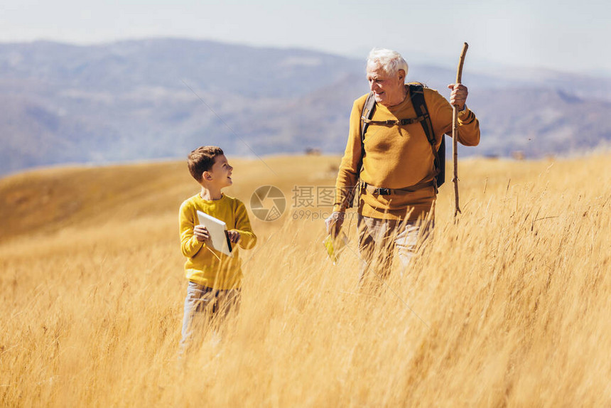 老人带着孙子在秋天的乡村散步图片