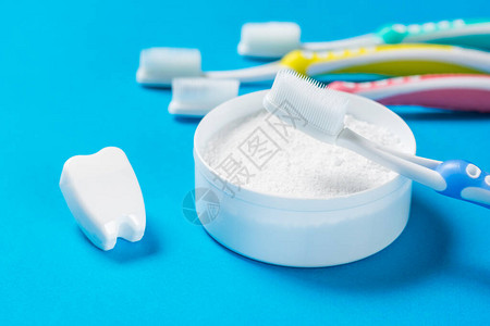 假牙一套硅胶牙刷和蓝底的牙齿清洁粉图片