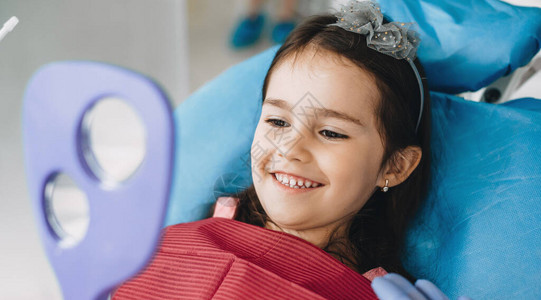 快乐的小女孩在牙医做手术后在镜图片