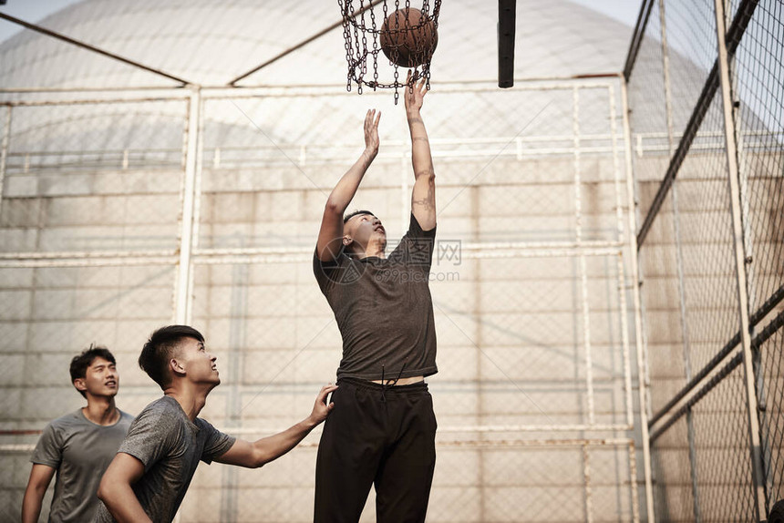 在户外法庭上打篮球的年轻图片