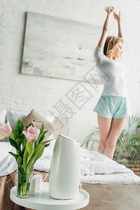 妇女用空气净化剂和鲜花在卧室中拉展有图片