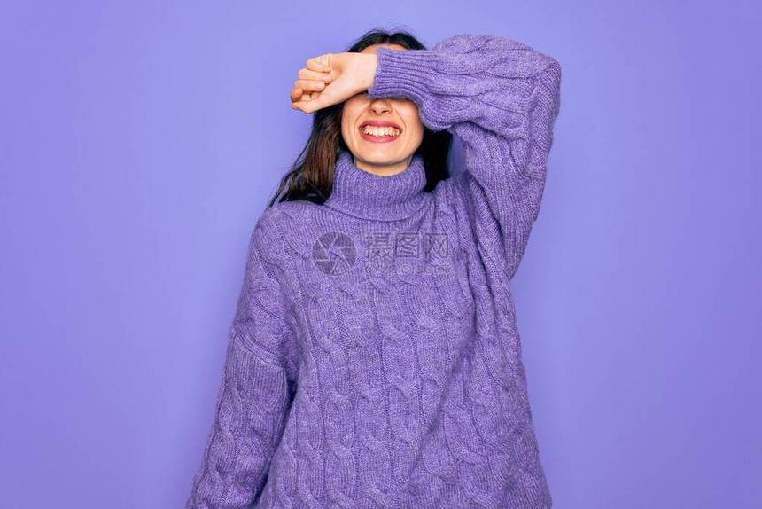 年轻漂亮的女人穿着休闲高领毛衣站在紫色的背景上图片