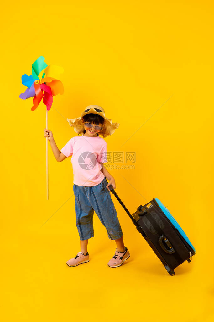 年轻亚洲漂亮女孩拿着多彩轮机和拖蓝色旅行袋的肖像图片