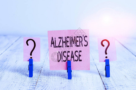 显示阿尔茨海默病的文字符号是疾病商业照片展示了老年时发生的高级精神退化用纸夹放在木桌上的潦草背景图片