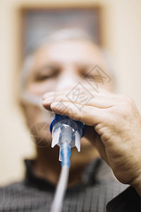高级男子使用医疗设备吸入呼吸道面具室内喷雾器的图片