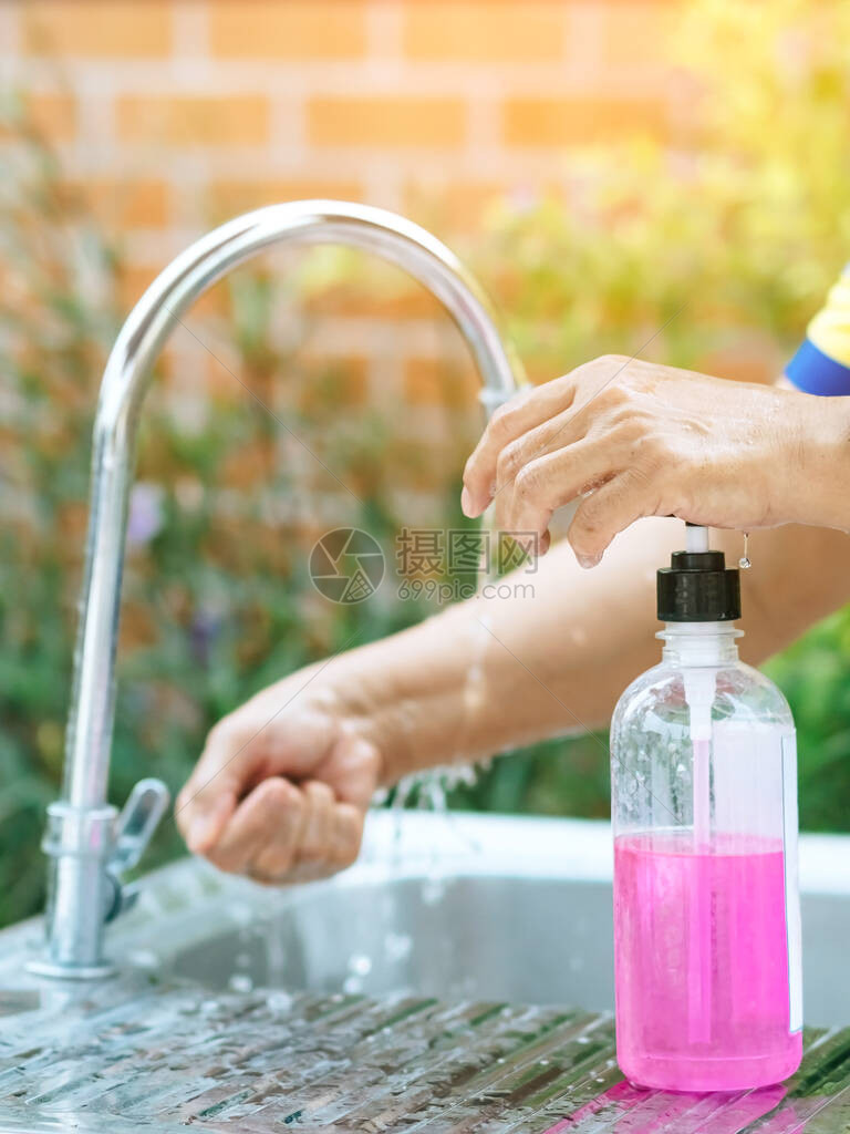 一名妇女用粉色肥皂在铝浴缸中洗手流感概念图片