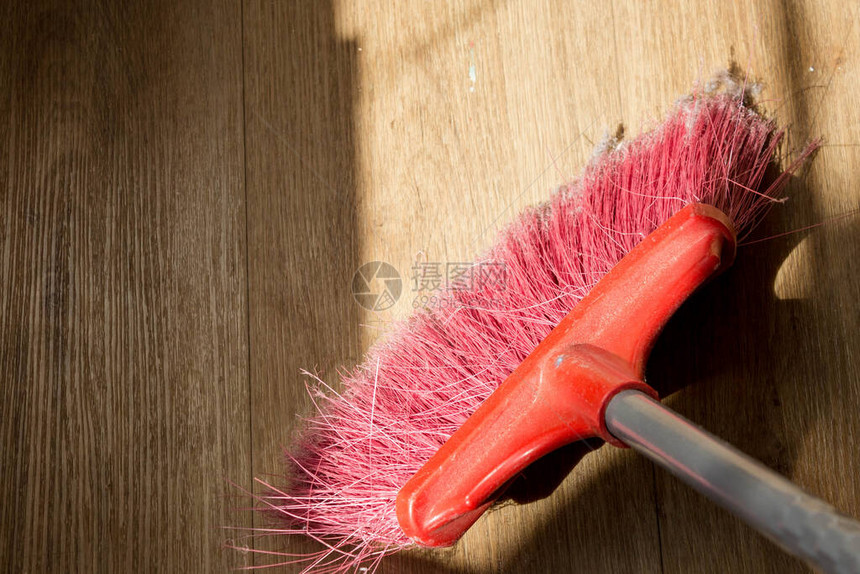 打扫房子的工具厨房乙烯基地板覆盖物背景上带有人造刷毛和长柄的红色扫刷图片