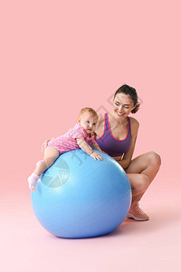 年轻运动的母亲和她的婴儿在彩色背景上与健图片