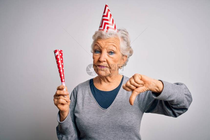 盛庆生日的高级灰色头发女士戴着笑帽带着满脸怒气的喇叭消极迹象显示不喜欢用拇指往下图片