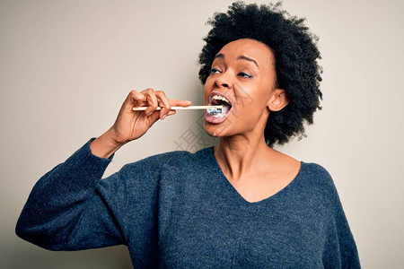 非洲裔美国妇女用牙刷和口腔膏刷牙清洁牙齿和舌头作为健康图片