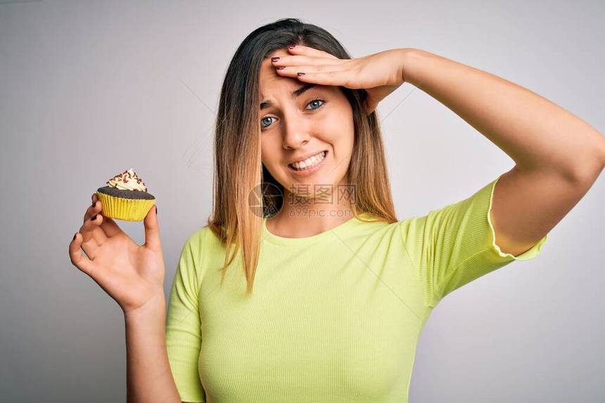 蓝眼睛的年轻美女在白色背景上吃着甜巧克力蛋糕图片