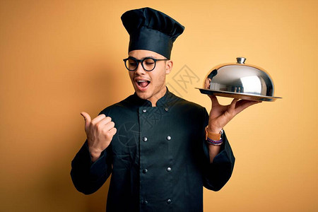身穿烹饪服戴帽子拿着圆顶的托盘图片