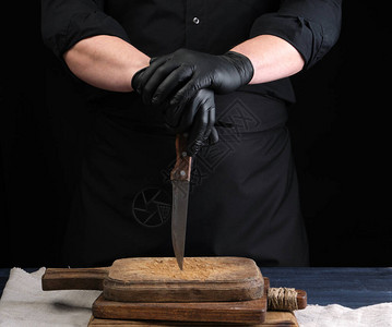 穿黑衬衫和黑色乳胶手套的厨师拿着一把老式厨房刀图片