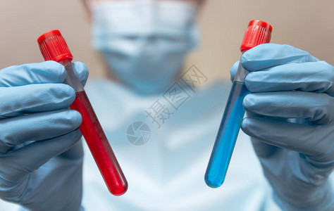 防护服医疗面具和乳胶手套医生持有血液和疫苗测试管图片