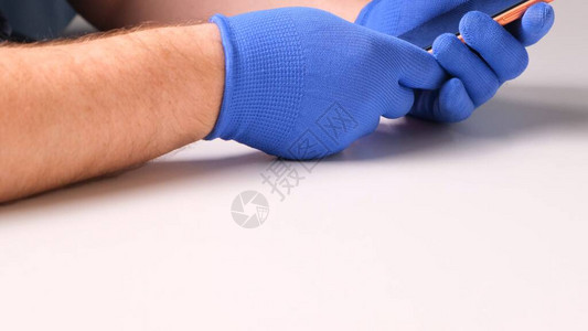 戴着蓝色手套的男手代替了智能手机破碎的钢化玻璃屏幕保护膜一个男人准备用智能手机代替玻璃智能手机维修理背景图片