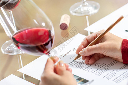 关闭了手拿着红酒杯在桌上的细节葡萄酒管家评估红酒图片