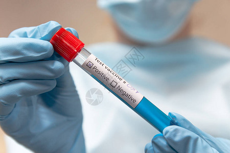 保护服医疗面罩和乳胶手套的医生拿着一个带有疫苗的测试管图片