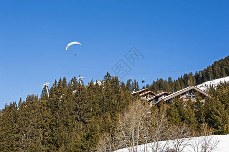 滑翔伞在雪上飞过高山度假胜地上面有图片