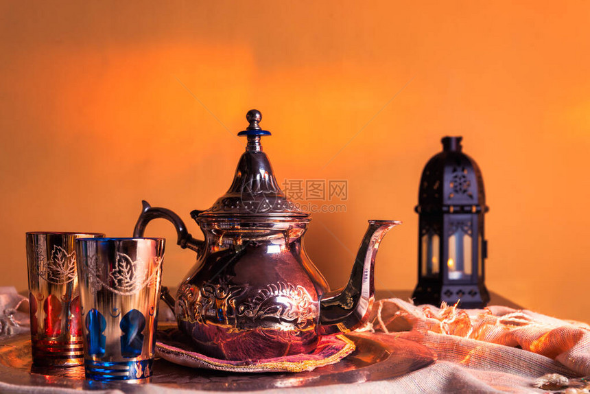 茶壶阿拉伯杯子和蜡烛在背图片