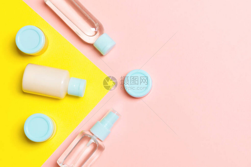 粉红色和黄色背景的不同化妆品瓶和化妆品容器的顶部视图具有复制空图片