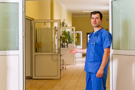 中年高加索白人身穿工作服的男医生站在医院走廊里图片