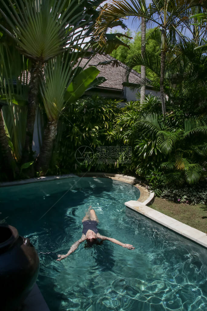 美丽的年轻女子在游泳池里放松的画像在私人别墅游泳池放松夏日豪华的图片