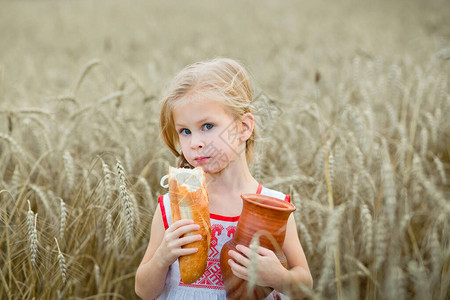 一个小孩在一个小麦田里配着一壶牛图片