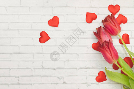 红花郁金香和红心在砖墙春天和节日妇女节图片