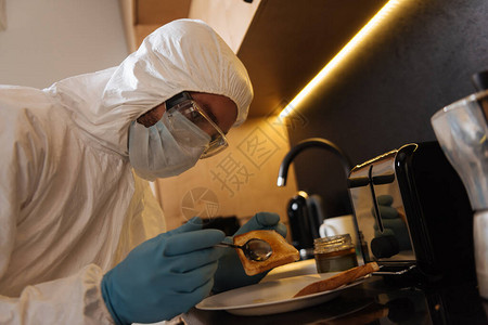 男子使用个人防护设备在厨房面包附近持图片