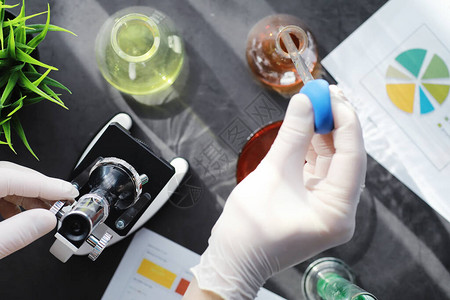 生化学家实验室研究药物测试在实验室进行化学实验在医务人员的桌子上用显微镜观察各背景