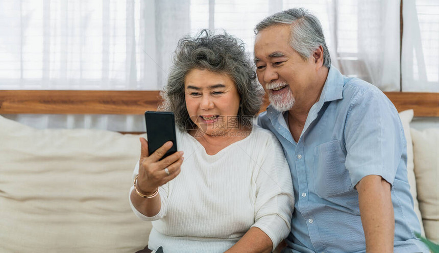 亚洲夫妇祖父母在家里用手机给孙子打电话或用快乐的感觉自拍图片