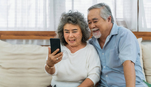 亚洲夫妇祖父母在家里用手机给孙子打电话或用快乐的感觉自拍图片