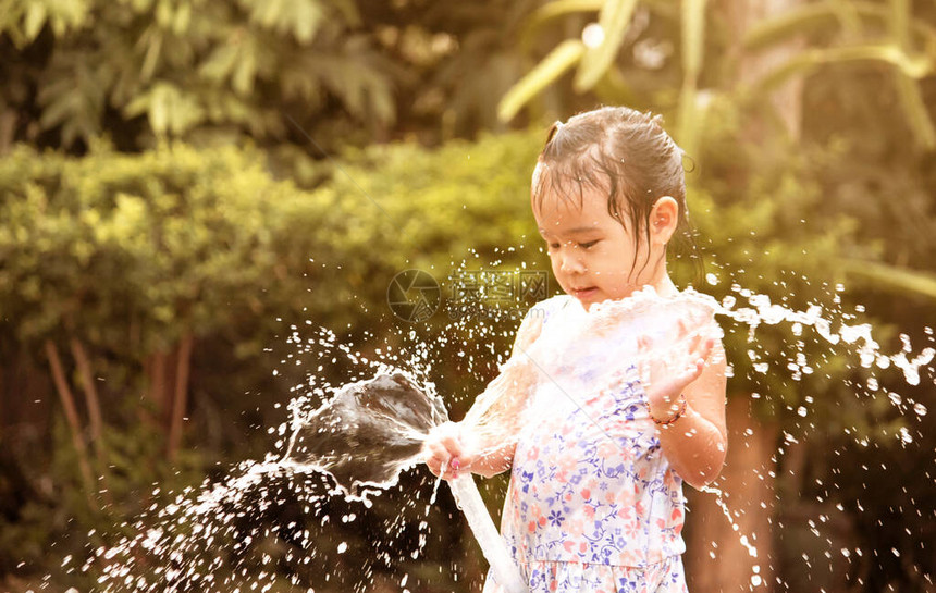 可爱的小女孩在后院打橡皮软管喷水图片