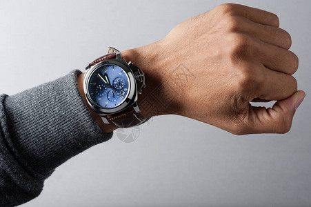 蓝色拨号的时装手表和男子手腕上的棕鳄图片