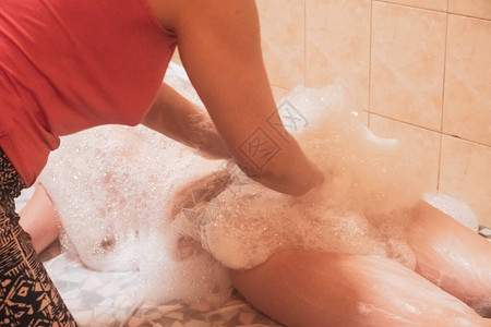 第比利斯的白种硫磺浴池一个女人在给一个女孩做肥皂按背景图片