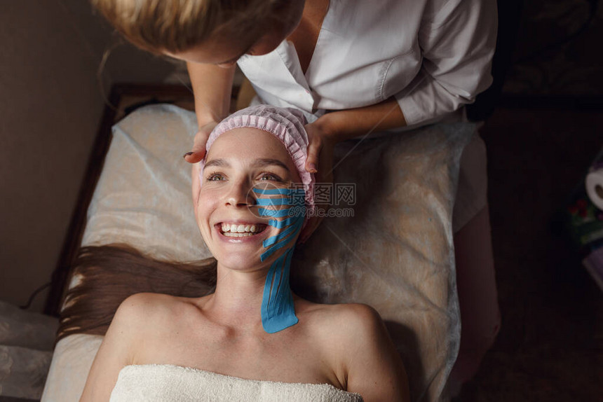 面对美学录音面部皮肤护理年轻女子躺在脸上贴着胶带减少额头和外眼角皱纹的无创抗图片