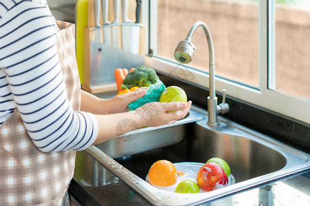 亚洲健康女在厨房水槽上清洗苹果和其他水果图片