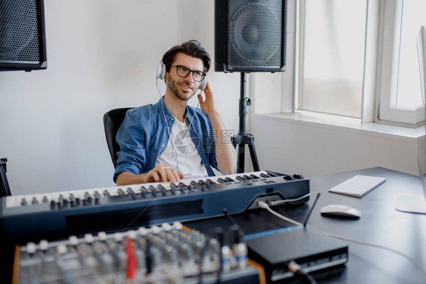 男音乐编曲手在数字录音室的midi钢琴和音频设备上创作歌曲人在家里的项目中制作电图片