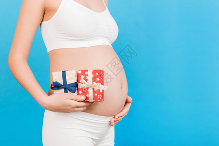 孕妇双手上的两个礼物盒紧贴着她的腹部图片