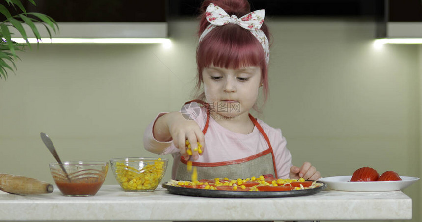 小女孩在面团中加入玉米罐头图片