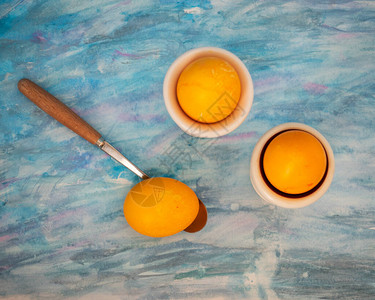 蓝纸背景的橘子鸡蛋鸡蛋摊和茶匙图片
