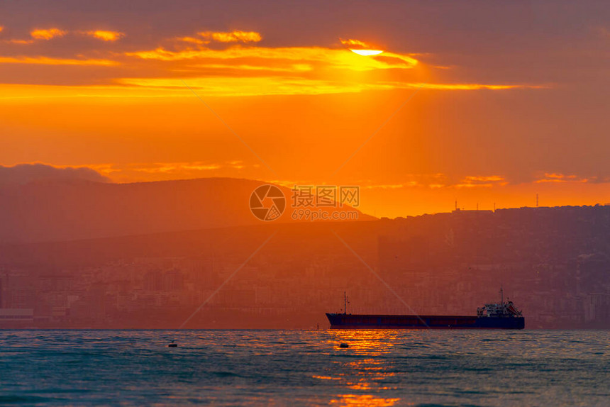 货船在金色的日落或日出时在海上航行太阳落山或升起时跨水海运大自然的和谐与美丽风景秀图片