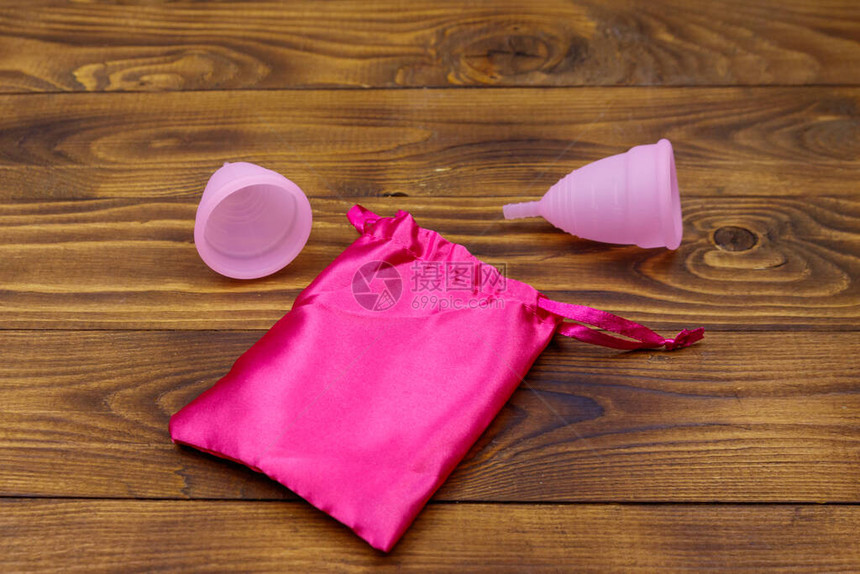 2个粉红可重复使用的硅酮月经杯和木本底的丝袋女卫生妇图片