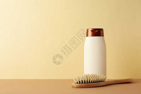 米色背景上的空白洗发水瓶和发刷图片